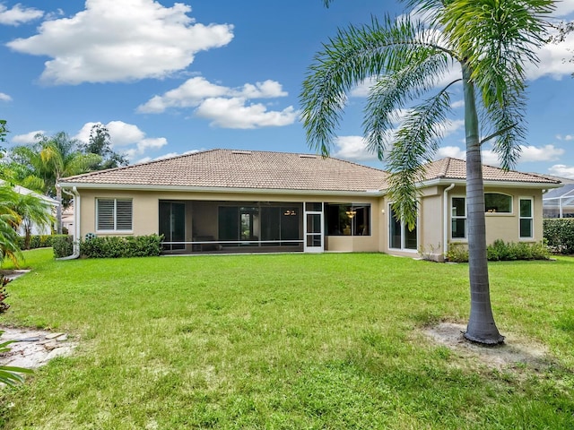 back of house with a sunroom, a lawn, a tiled roof, and stucco siding