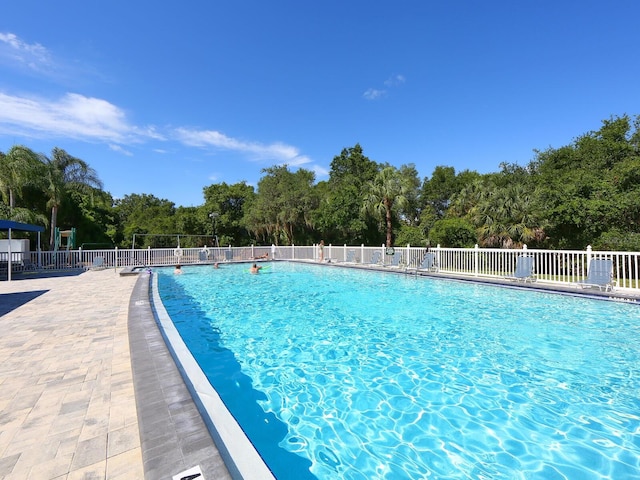 pool with a patio area and fence