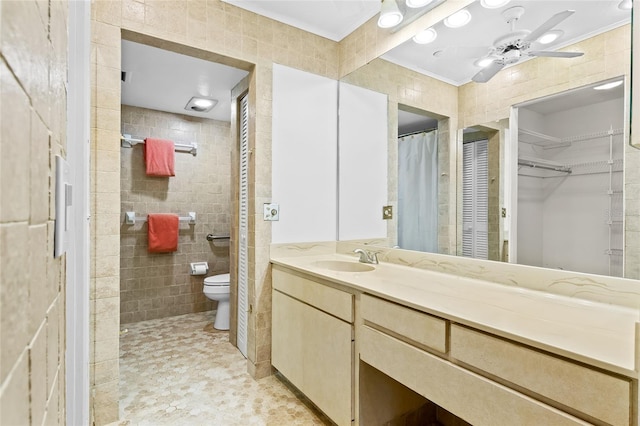 bathroom with toilet, crown molding, vanity, tile walls, and ceiling fan