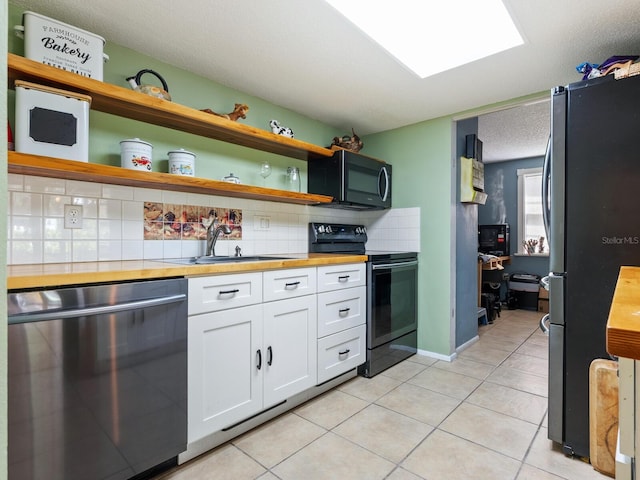 kitchen with white cabinetry, butcher block counters, stainless steel appliances, sink, and decorative backsplash