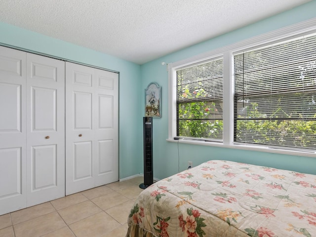 bedroom with a textured ceiling, light tile patterned floors, and a closet