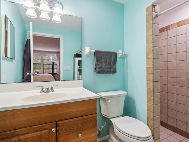 bathroom with tile patterned floors, toilet, a tile shower, and vanity