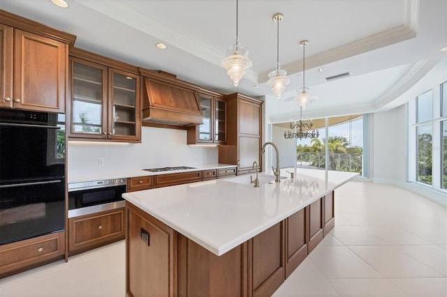 kitchen with gas stovetop, a raised ceiling, a notable chandelier, black double oven, and custom exhaust hood