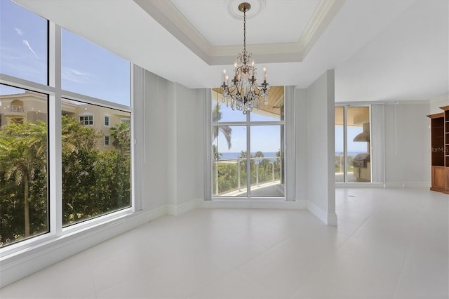 unfurnished dining area featuring a tray ceiling, an inviting chandelier, plenty of natural light, and crown molding