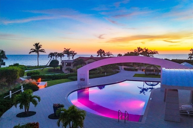 pool at dusk featuring a water view