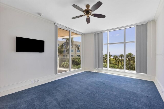 carpeted empty room featuring a wall of windows, plenty of natural light, ceiling fan, and ornamental molding