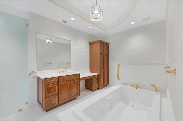 bathroom with a chandelier, vanity, a raised ceiling, and a bathtub