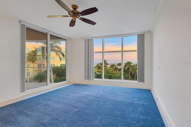 spare room with carpet flooring, a wall of windows, ceiling fan, and ornamental molding