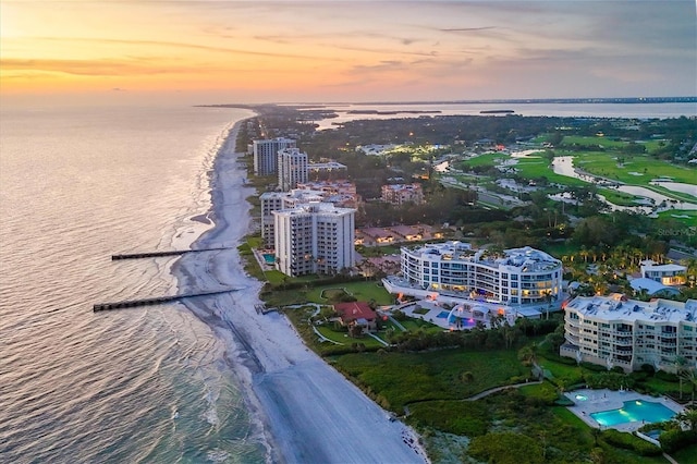 aerial view at dusk with a beach view and a water view