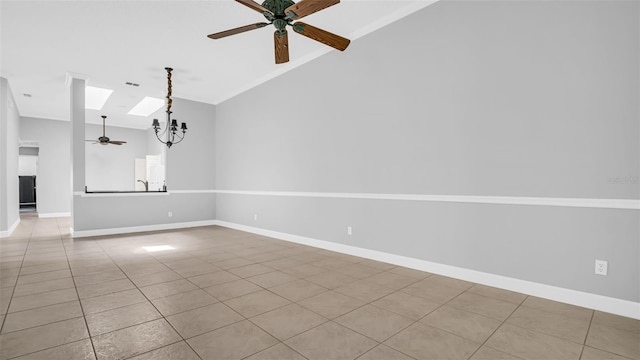 tiled spare room with ceiling fan with notable chandelier and vaulted ceiling with skylight