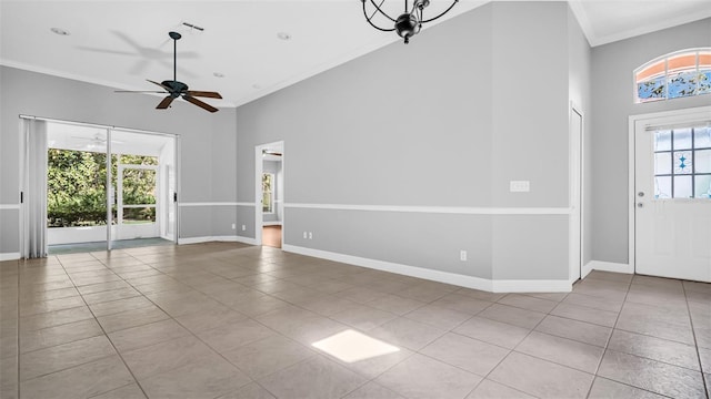 unfurnished living room with light tile patterned floors, ceiling fan with notable chandelier, and ornamental molding