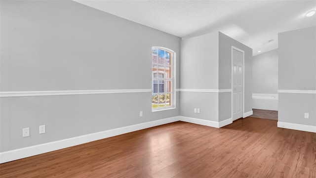 empty room featuring wood-type flooring and a textured ceiling