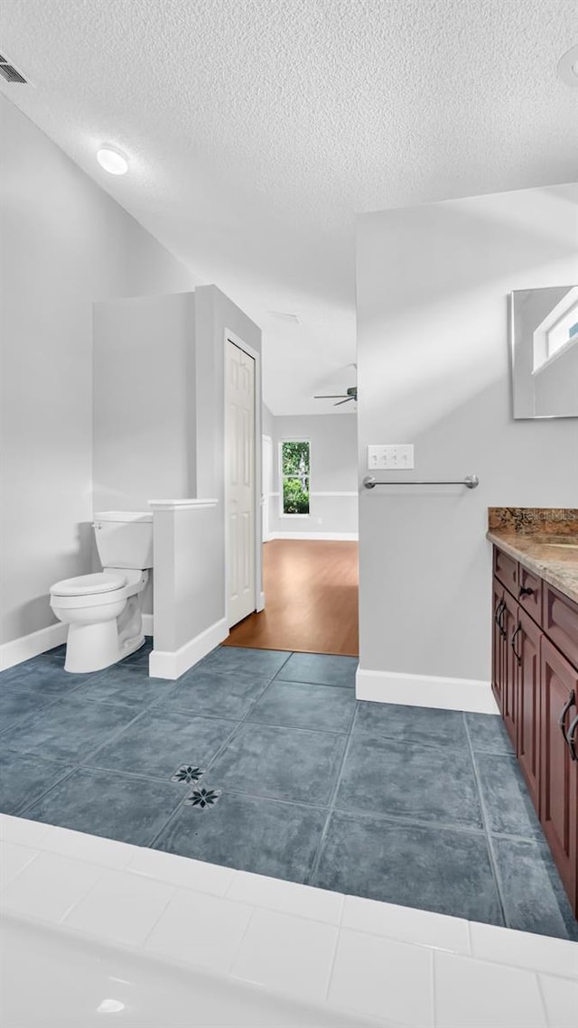 bathroom with vanity, ceiling fan, a textured ceiling, and toilet