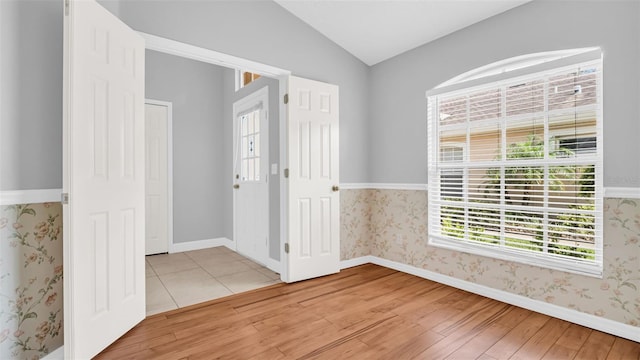 spare room with vaulted ceiling and light wood-type flooring