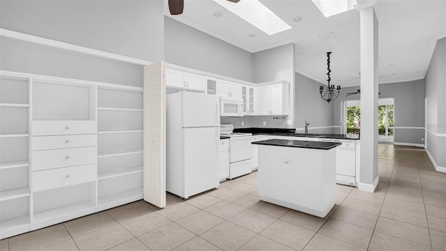 kitchen featuring white appliances, white cabinetry, a kitchen island, lofted ceiling with skylight, and light tile patterned flooring