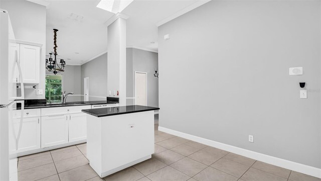 kitchen featuring sink, ornamental molding, white cabinets, a kitchen island, and decorative light fixtures