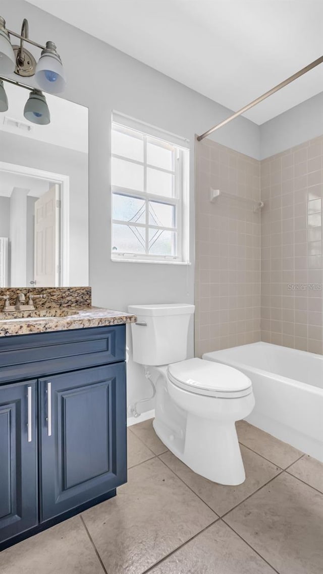 full bathroom featuring vanity, tiled shower / bath combo, tile patterned floors, and toilet