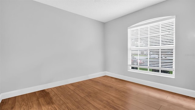 unfurnished room with hardwood / wood-style flooring and a textured ceiling