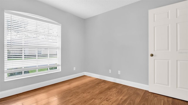 unfurnished room featuring wood-type flooring and a textured ceiling