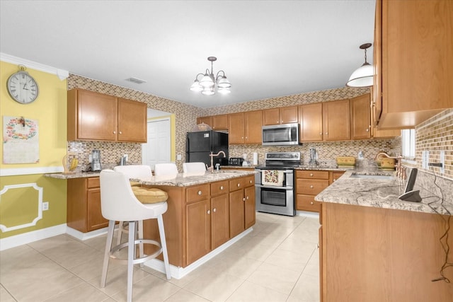 kitchen with sink, appliances with stainless steel finishes, hanging light fixtures, light stone countertops, and a center island with sink