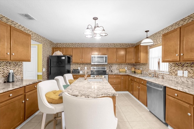 kitchen with sink, a breakfast bar area, decorative light fixtures, appliances with stainless steel finishes, and a kitchen island