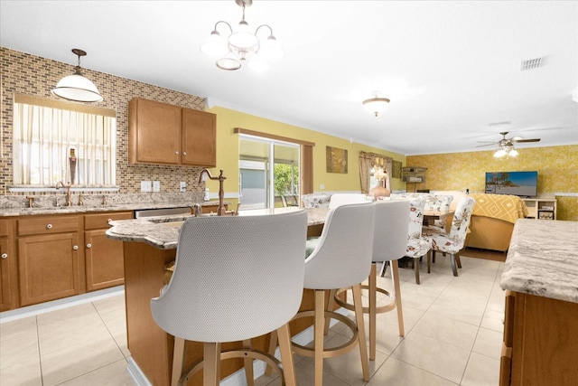 kitchen with a center island, decorative light fixtures, light stone countertops, and sink