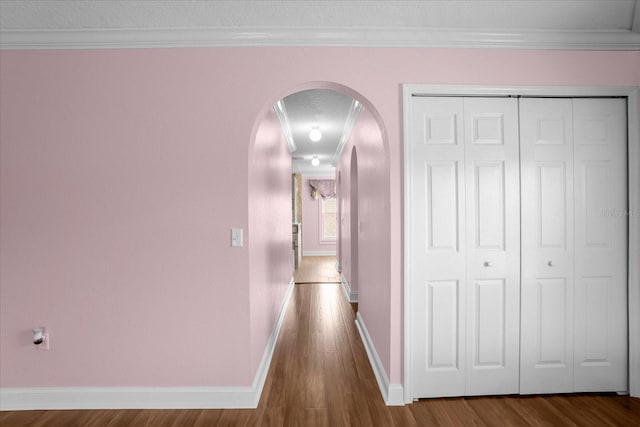 corridor featuring ornamental molding, wood-type flooring, and a textured ceiling