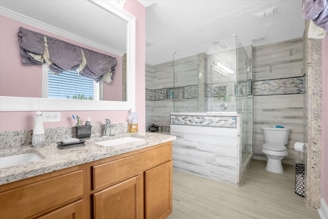 bathroom featuring vanity, ornamental molding, toilet, and a shower with shower door