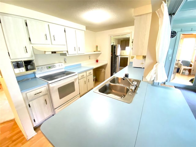 kitchen with stainless steel refrigerator, white range with electric cooktop, light hardwood / wood-style floors, and sink