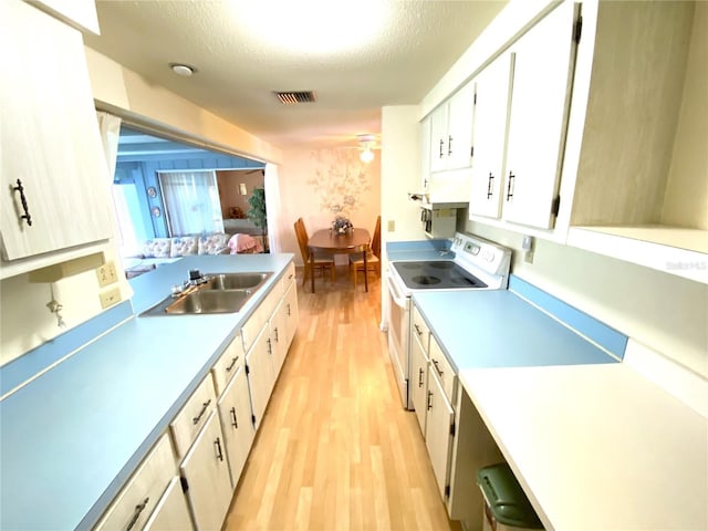 kitchen featuring sink, a textured ceiling, light wood-type flooring, electric stove, and white cabinets