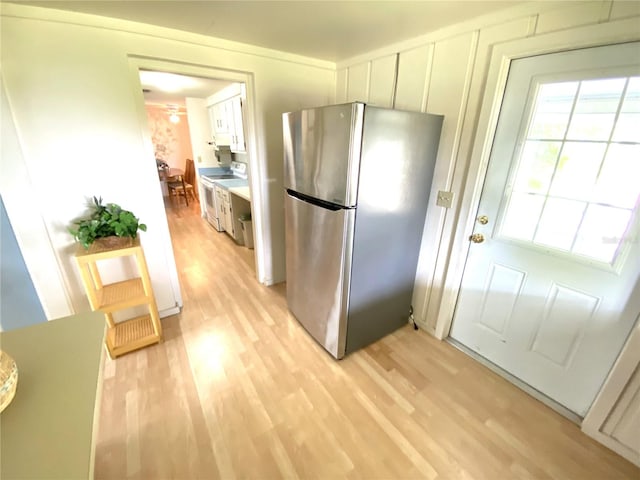 kitchen featuring stainless steel refrigerator, white electric range oven, light hardwood / wood-style flooring, and white cabinets