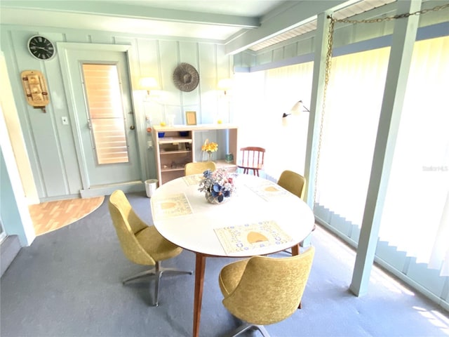 dining space featuring beamed ceiling and carpet