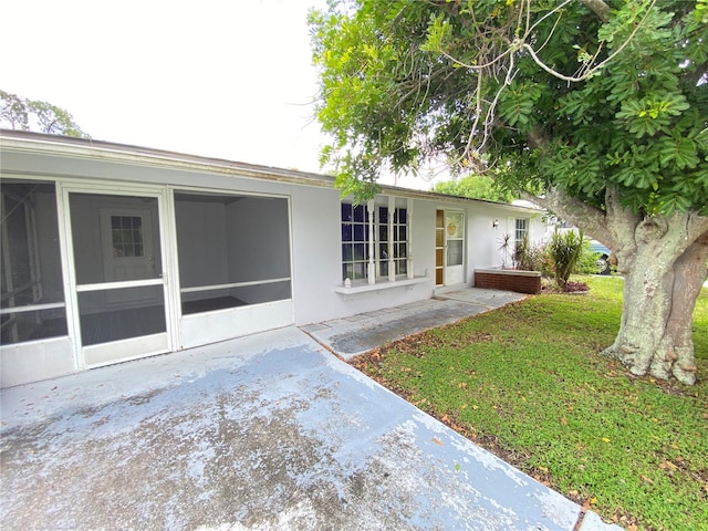 rear view of house with a yard, a patio area, and a sunroom