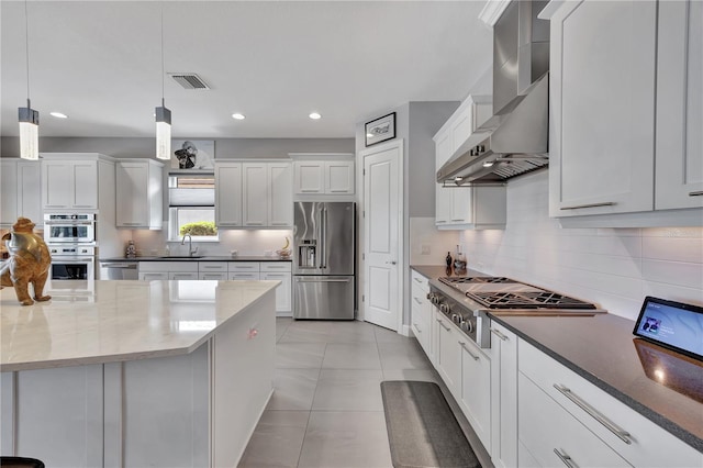 kitchen with appliances with stainless steel finishes, white cabinetry, dark stone countertops, and decorative light fixtures