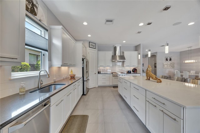 kitchen with wall chimney exhaust hood, appliances with stainless steel finishes, sink, and plenty of natural light