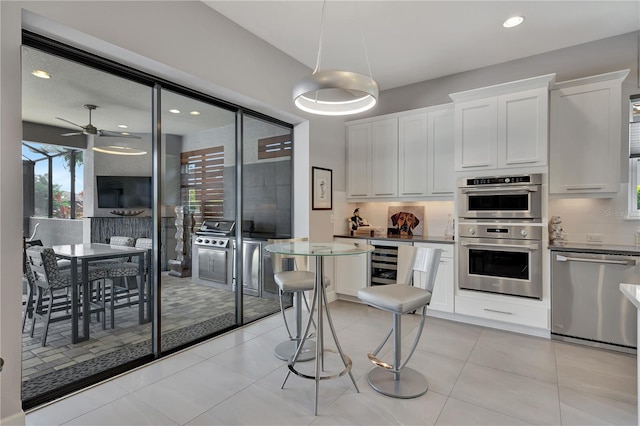 kitchen featuring white cabinets, tasteful backsplash, ceiling fan, appliances with stainless steel finishes, and light tile patterned flooring