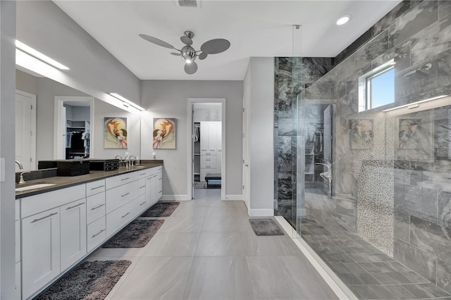 bathroom with a tile shower, tile patterned flooring, vanity, and ceiling fan