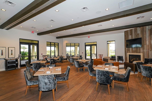 dining area with hardwood / wood-style flooring, beam ceiling, and a healthy amount of sunlight