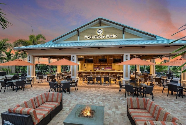 patio terrace at dusk with an outdoor living space with a fire pit and a bar