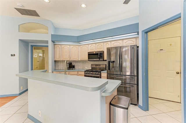 kitchen with light tile patterned floors, tasteful backsplash, light brown cabinets, appliances with stainless steel finishes, and sink