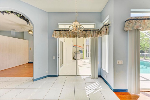 unfurnished dining area featuring ceiling fan with notable chandelier and tile patterned flooring