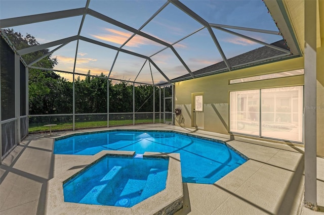 pool at dusk with a patio, glass enclosure, and an in ground hot tub