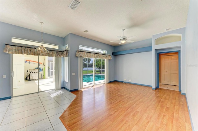 unfurnished room featuring a textured ceiling, hardwood / wood-style floors, and ceiling fan with notable chandelier