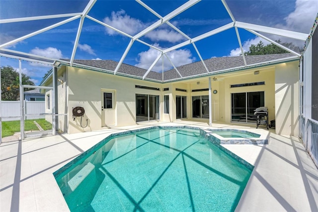 view of pool featuring glass enclosure, a patio, ceiling fan, and an in ground hot tub