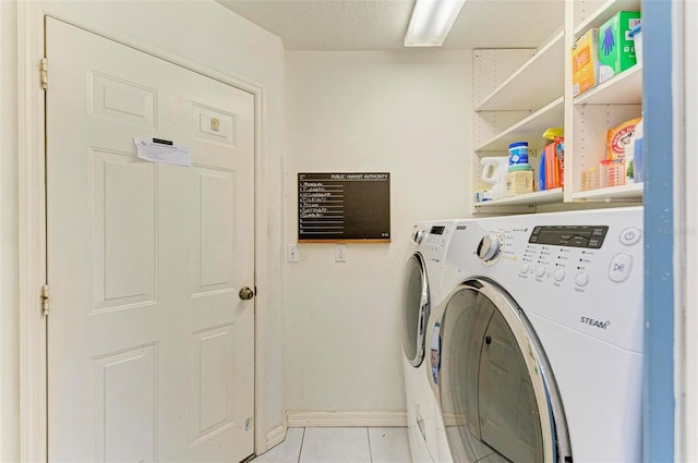 laundry room featuring washer and dryer, light tile patterned flooring, and a textured ceiling