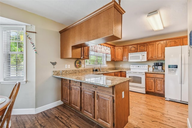 kitchen featuring light hardwood / wood-style floors, light stone counters, white appliances, and a healthy amount of sunlight