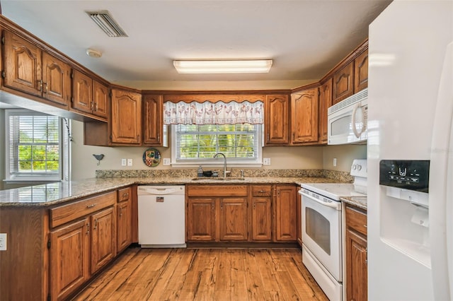 kitchen featuring sink, light hardwood / wood-style flooring, light stone counters, white appliances, and kitchen peninsula