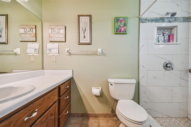 bathroom with tile patterned floors, a tile shower, vanity, and toilet