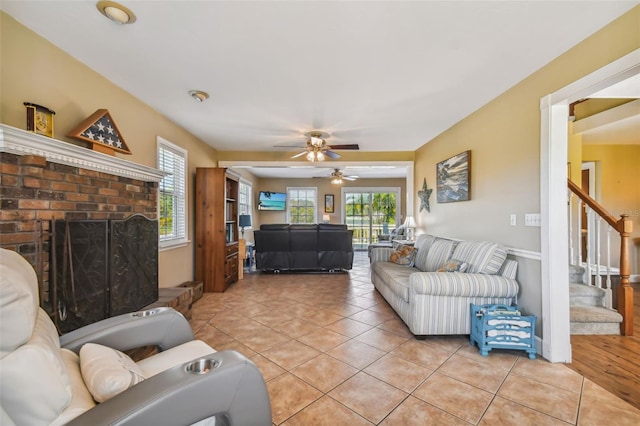 living room with a wealth of natural light, a brick fireplace, light hardwood / wood-style floors, and ceiling fan