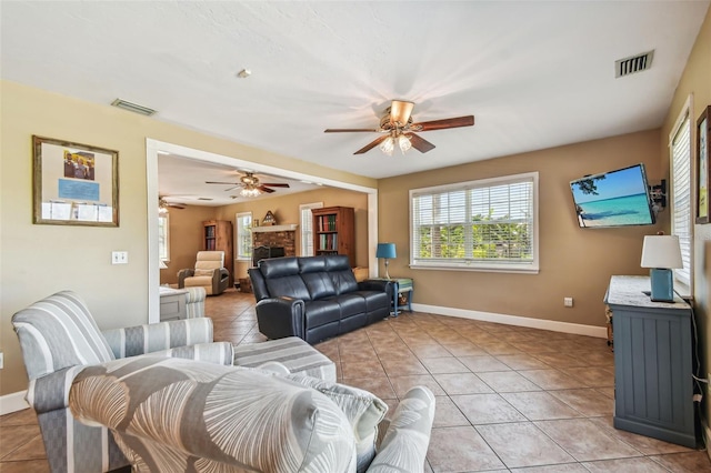 tiled living room with ceiling fan and a brick fireplace